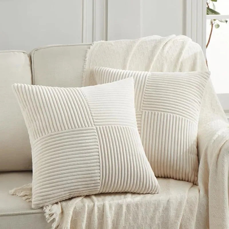 Two cream-colored, vertically ribbed patchwork throw pillow covers draped on a light sofa.