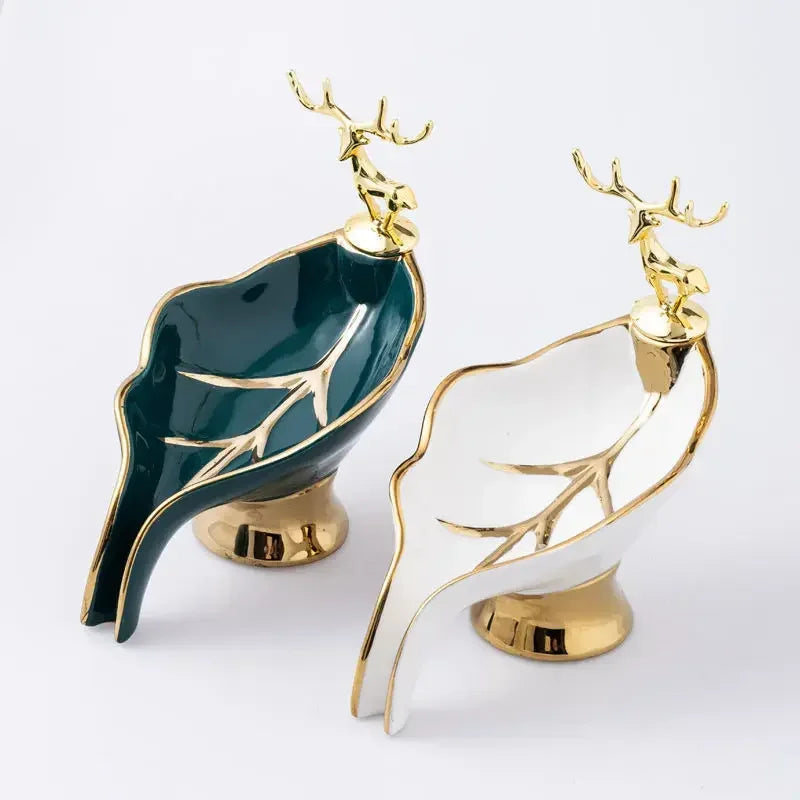 A leaf-shaped ceramic soap dish featuring gold accents and a deer antler drain rack.