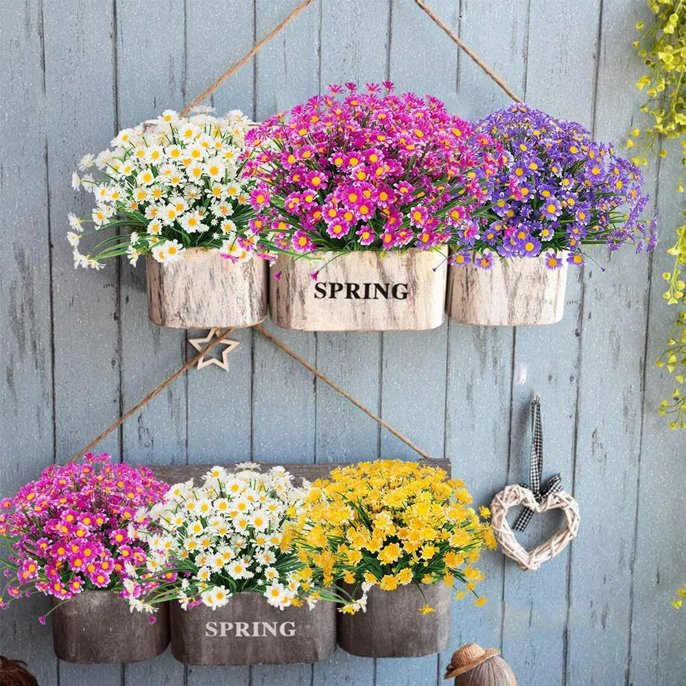 Darstellung farbenfroher künstlicher Margeriten in rosa, weiß und lila in Holzpflanzgefäßen.