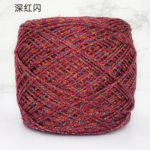 A ball of deep red metallic silk crochet yarn with an intricate woven texture.