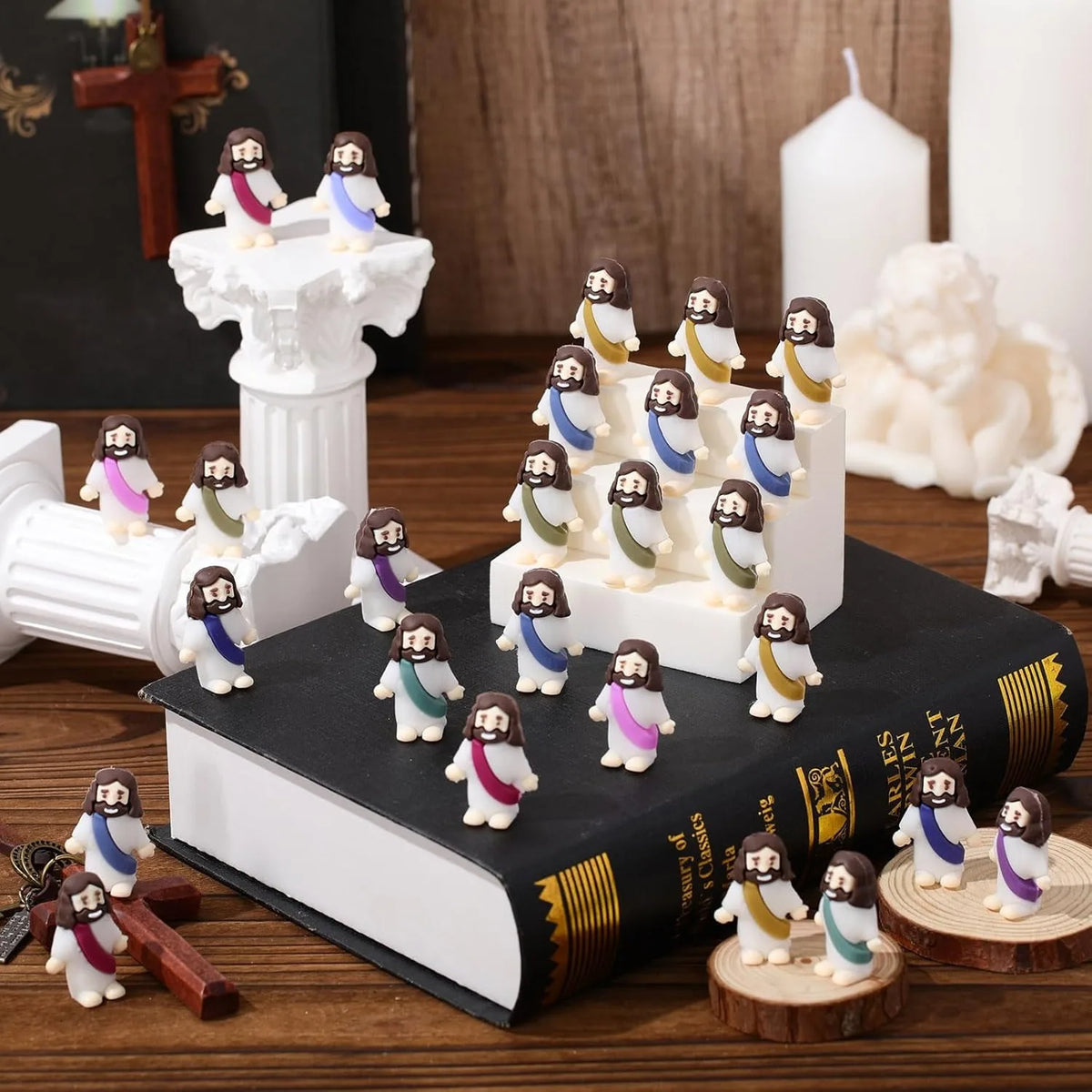 A collection of mini Jesus figurines in various colors and sizes displayed on a dark book and white pedestal.