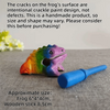 A handcrafted wooden frog percussion instrument with colorful crackle paint on a gray surface.