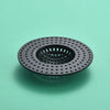 A black silicone sink drain filter strainer with a perforated design, shown against a light green background.