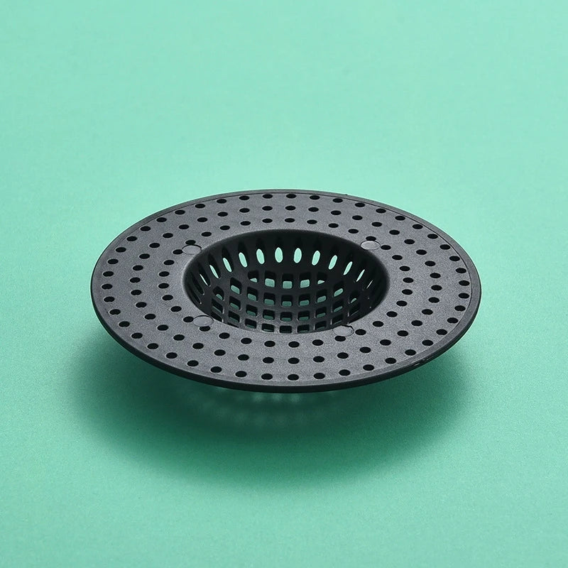 A black silicone sink drain filter strainer with a perforated design, shown against a light green background.