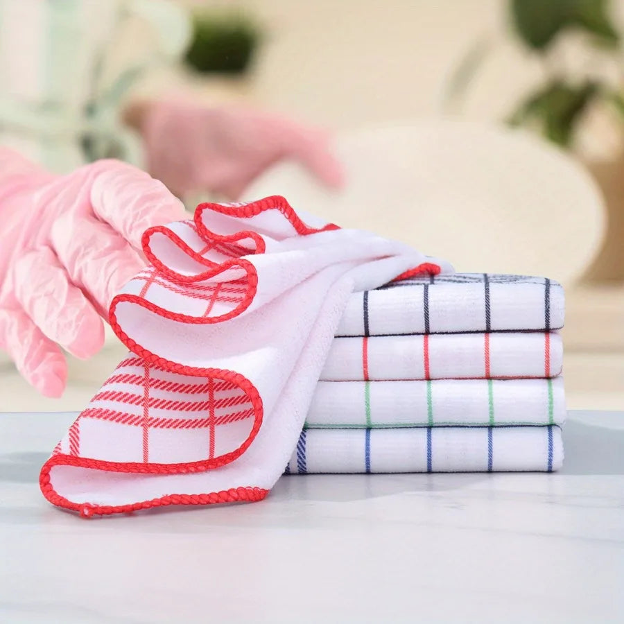 Pink gloved hand holding a stack of white and red checkered lint-free dish cloths on a white surface.