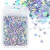 A clear plastic bag filled with shiny holographic star sequins and loose sequins scattered nearby.