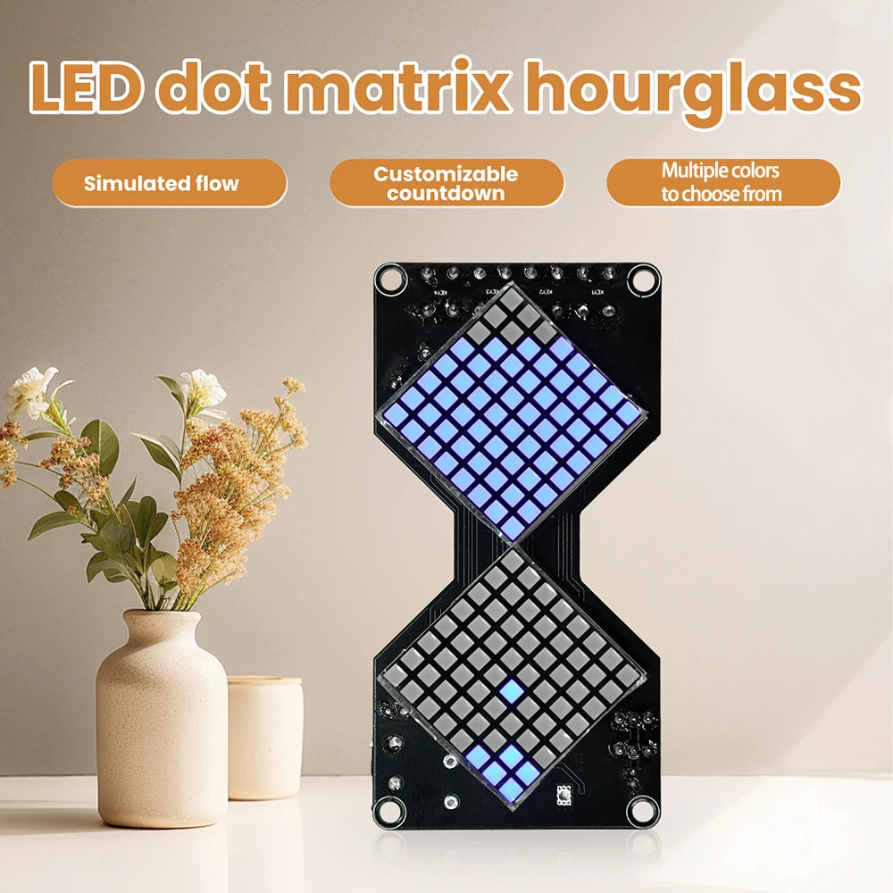 A black LED dot matrix hourglass display is shown on a white surface next to a potted plant.