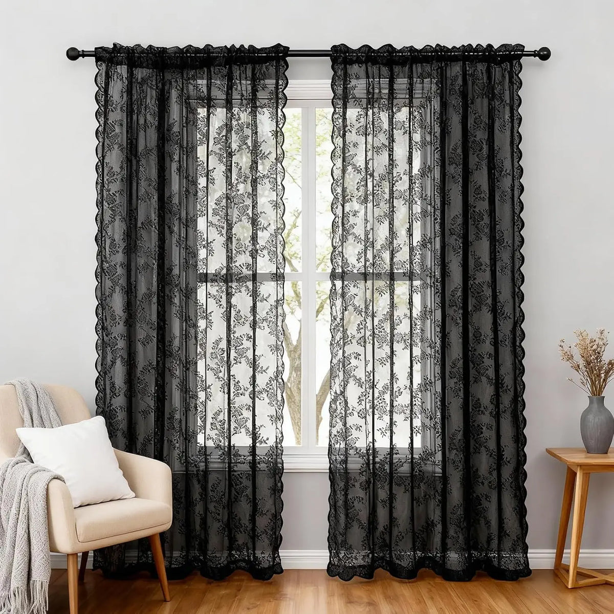 Black sheer floral lace curtains in two panels hanging over a white window.