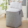 A quilted storage bag with handles in a black and white houndstooth pattern sits on the floor.