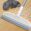 A silver detachable broom with a silicone scraper is shown next to a gray kitten on a wooden floor.