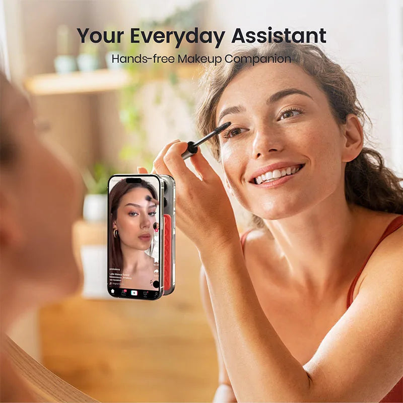 A woman is using a hands-free silicone suction cup phone mount to apply makeup while looking in a mirror.