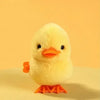 A yellow wind-up walking chicken toy with orange feet against a light background.