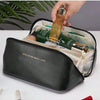 A black leather travel makeup organizer bag is open, showing a gold perfume bottle and other cosmetics inside.