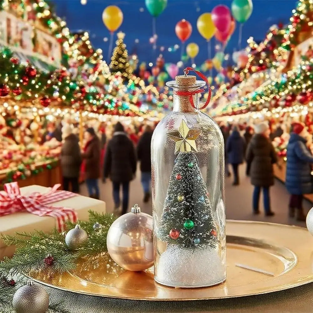 A glass bottle shaped like a Christmas tree with a snowy scene and a gold-colored ornament on a platter.