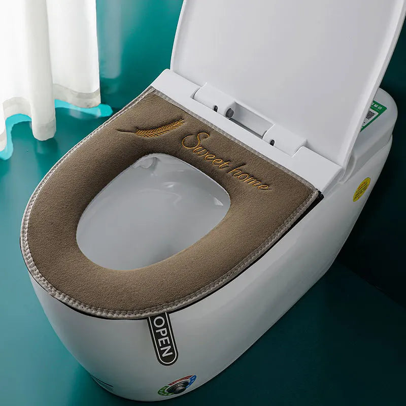 Asiento de inodoro blanco con cubierta impermeable beige y abierta, mostrando el tazón blanco limpio.