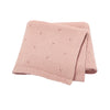A folded light pink knitted cotton baby blanket with small eyelet details.