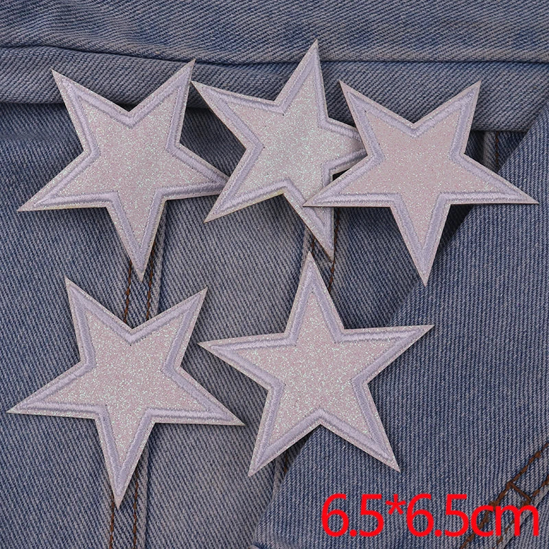 A set of five silver glitter star iron-on embroidered patches displayed on a denim fabric.