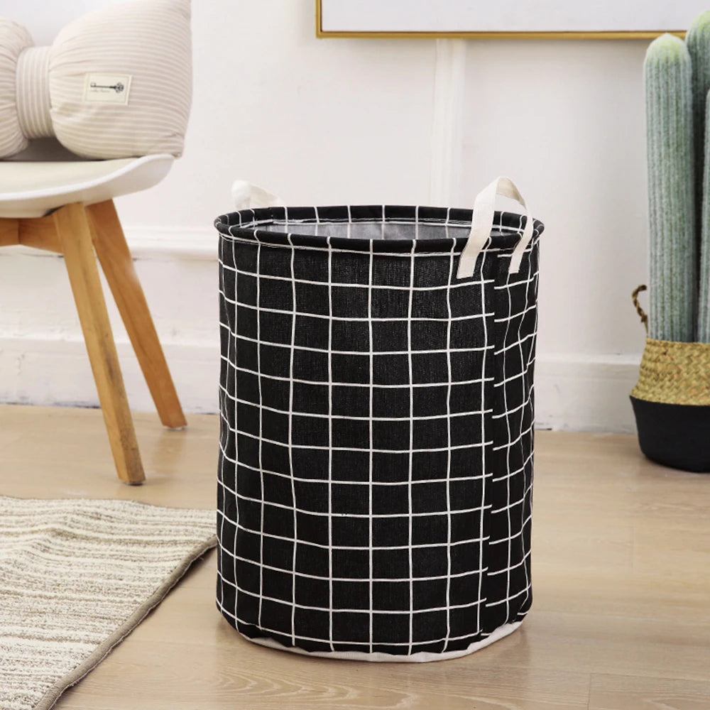 A black and white checkered fabric laundry basket with handles sitting on a wooden floor.