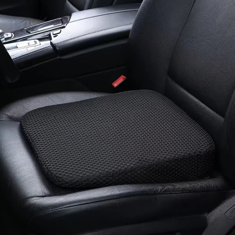 A black ergonomic height-increasing car seat cushion is shown in a vehicle interior.