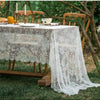 Elegant white lace tablecloth with French retro floral design set up outdoors for an event.