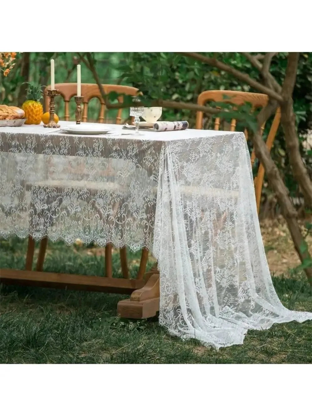 Elegant white lace tablecloth with French retro floral design set up outdoors for an event.