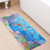 A colorful cartoon bathtub mat featuring sea creatures like a whale, fish, and pink octopus on a tiled floor.