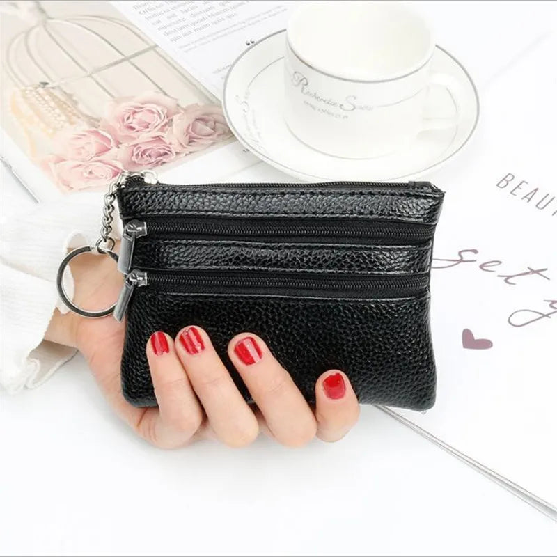 A black quilted PU leather two-zip coin purse is held by a hand next to a white cup and some pink roses.