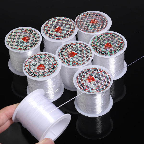 Rolls of white nylon beading cord for jewelry making stacked on a black surface.