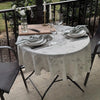 A white cotton-linen tablecloth with a rustic fern print is set for a meal outdoors on a patio table.