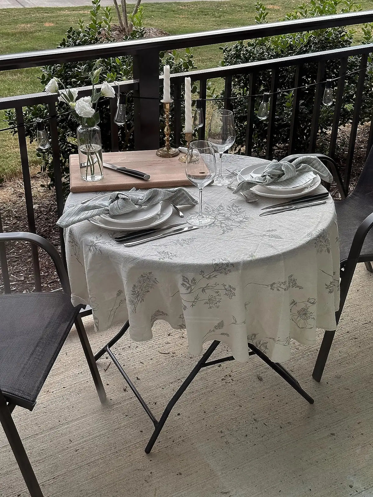 A white cotton-linen tablecloth with a rustic fern print is set for a meal outdoors on a patio table.