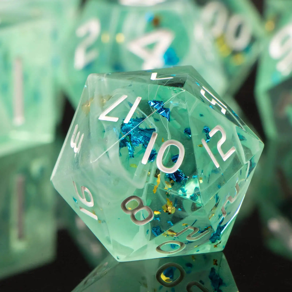 A close-up of a translucent mint green polyhedral die resting on a dark surface, surrounded by other dice.