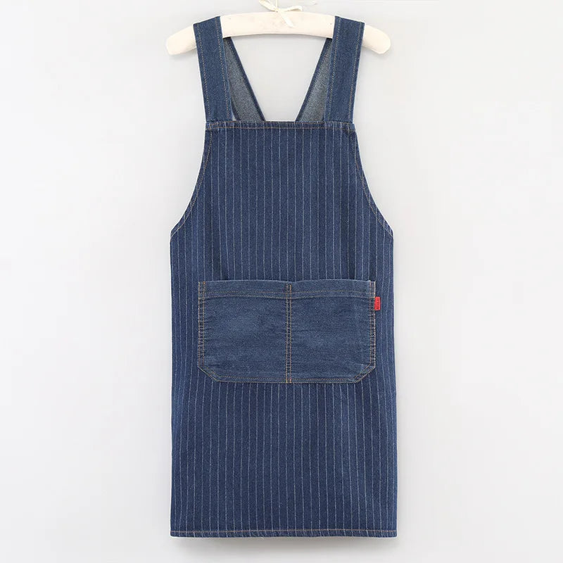 A navy blue striped denim cross-back apron hanging on a wooden hanger.