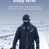 A person wearing a black windproof full face balaclava mask and jacket is cycling outdoors in the snow.