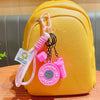 A yellow backpack with a pink fitness keychain attached to the zipper pull.