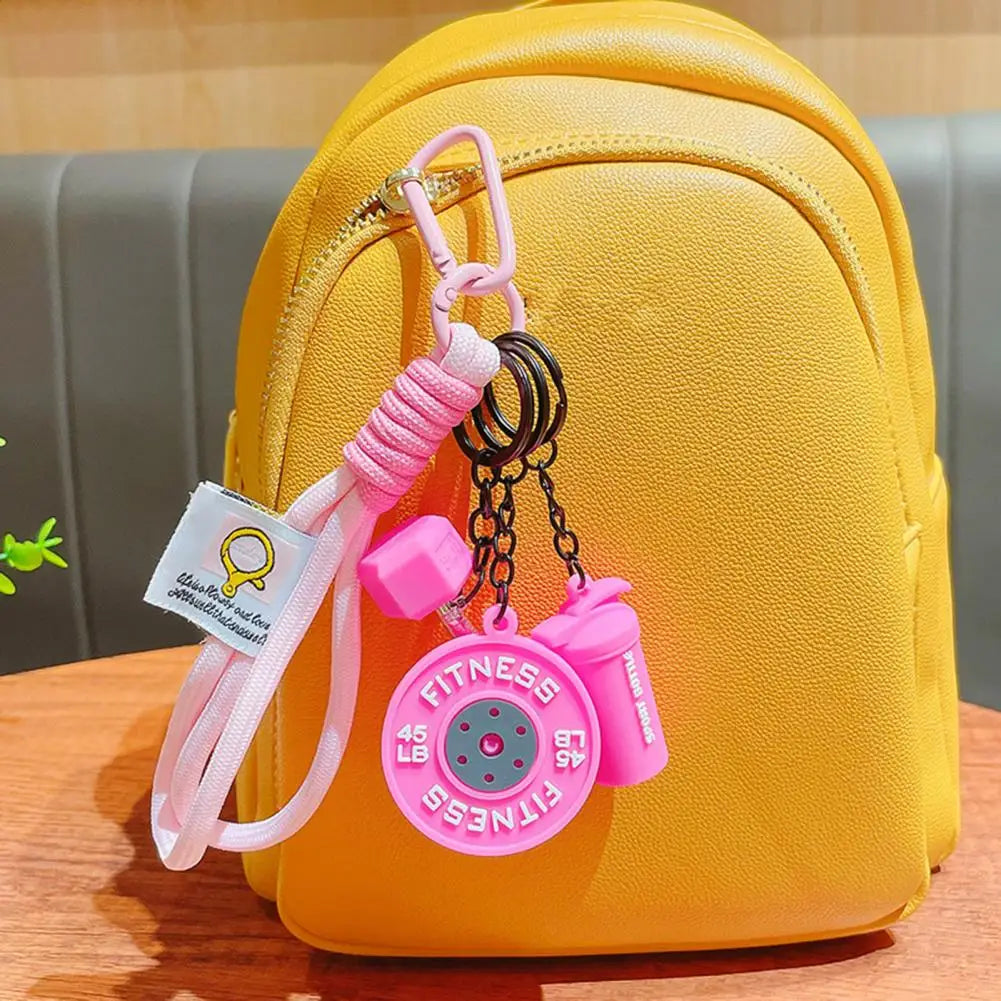 A yellow backpack with a pink fitness keychain attached to the zipper pull.