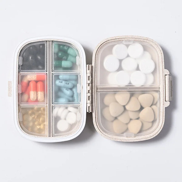 A clear weekly pill organizer with eight compartments filled with various colored and white pills.