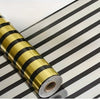 Roll of luxury mirror embossed wall panels in gold and black stripes on a surface.