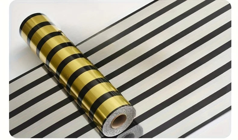 Roll of luxury mirror embossed wall panels in gold and black stripes on a surface.
