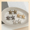 A collection of silver and gold star-shaped metal brooches arranged on a white plate.