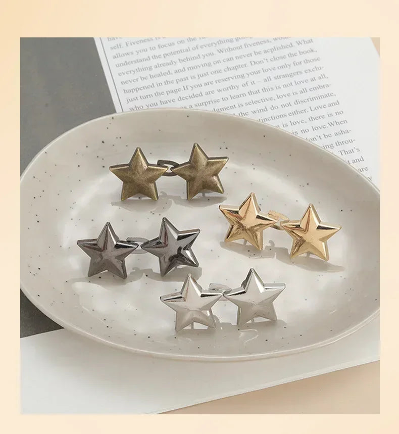 A collection of silver and gold star-shaped metal brooches arranged on a white plate.
