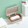 A pink transparent soap dish with a drainage tray and lid is shown on a white surface.