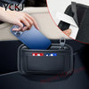 A hand places a smartphone into a black car seat organizer pocket, demonstrating its storage function.