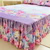 A floral print bed skirt and pillowcase set featuring shades of pink, purple, and green flowers.