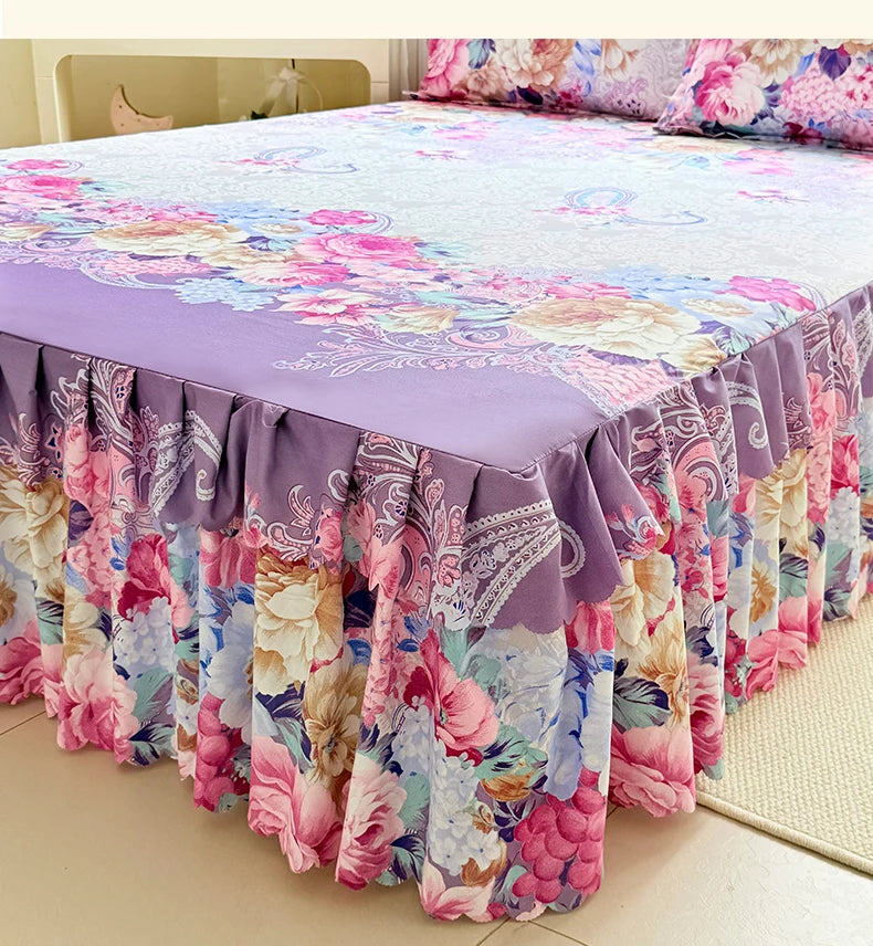 A floral print bed skirt and pillowcase set featuring shades of pink, purple, and green flowers.