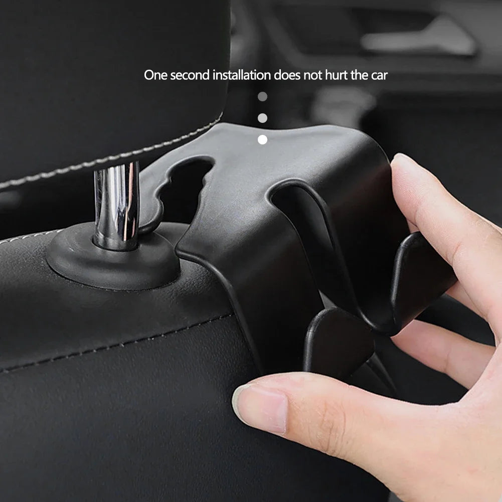 A hand is installing a black car headrest hook into a black leather handbag.