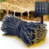 A bundle of black solar powered outdoor string lights with gold tips and wires, ready for use.