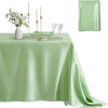 A light green satin tablecloth set for dining featuring a centerpiece of white flowers, candles, and glassware.
