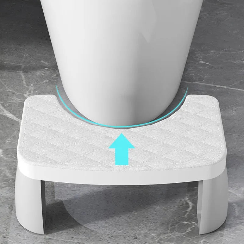 A white ergonomic non-slip toilet squat stool with a padded seat and a blue arrow indicating the direction of movement.