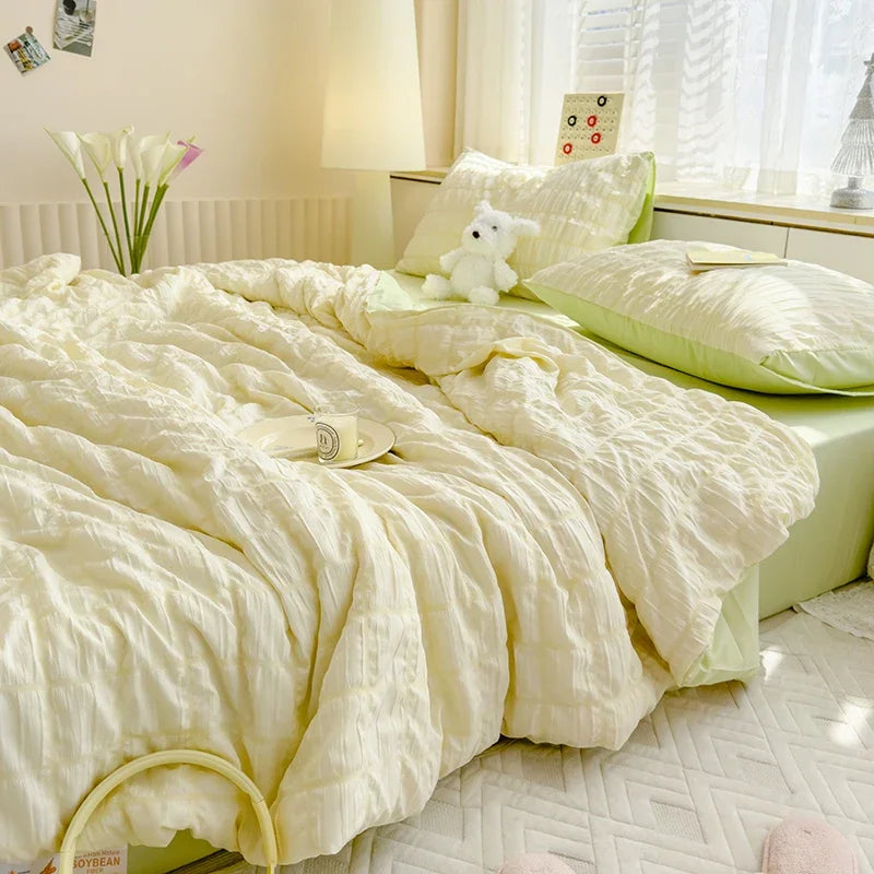 A light yellow breathable summer seersucker quilt spread on a bed with white bedding and a small white stuffed animal.