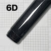 A close-up view of a black carbon fiber vinyl wrap film displaying a glossy finish on a grid background.